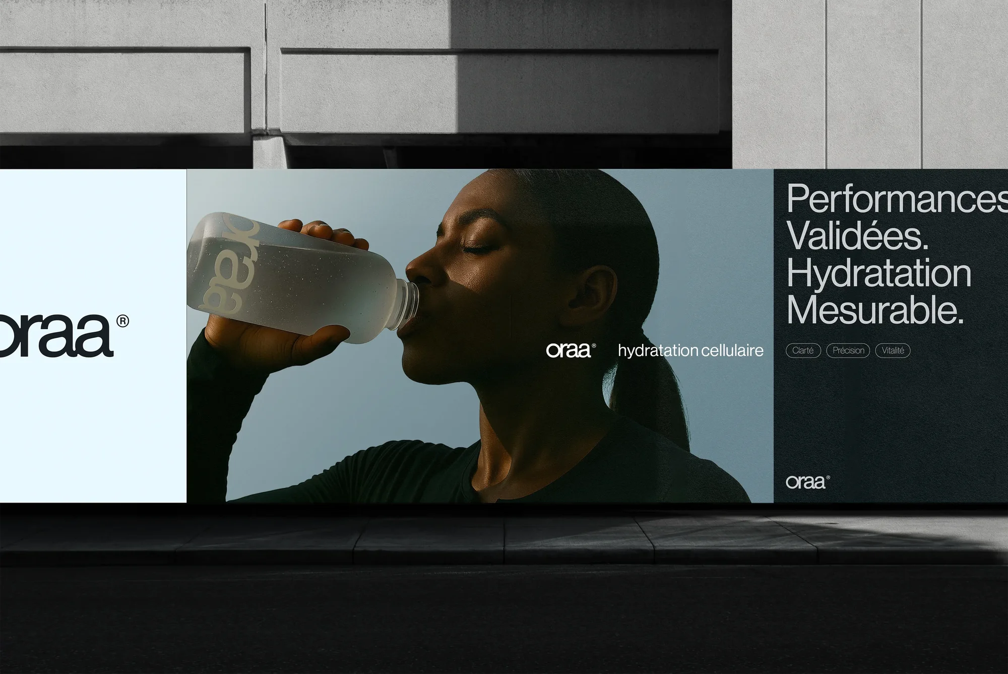 Billboard ad for Oraa hydration drink featuring a woman drinking from a clear bottle against a gradient blue sky background.