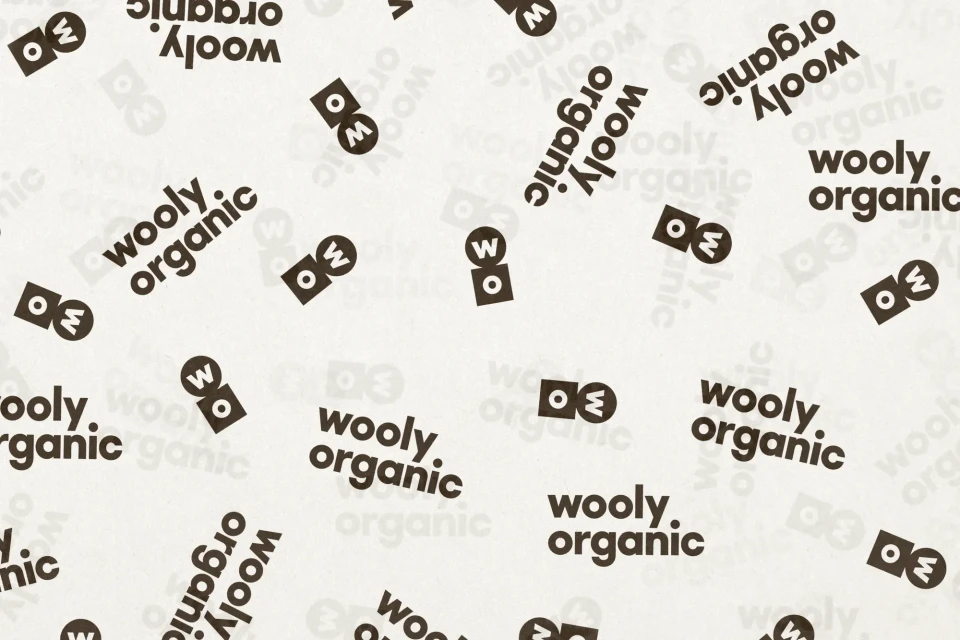 Scattered logos of 'wooly organic' against a light beige background create a visually repeating branded pattern.