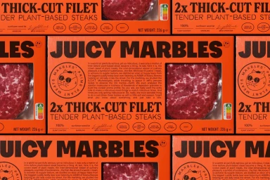 Bright orange Juicy Marbles plant-based steak product packaging boxes tiled uniformly in the frame.