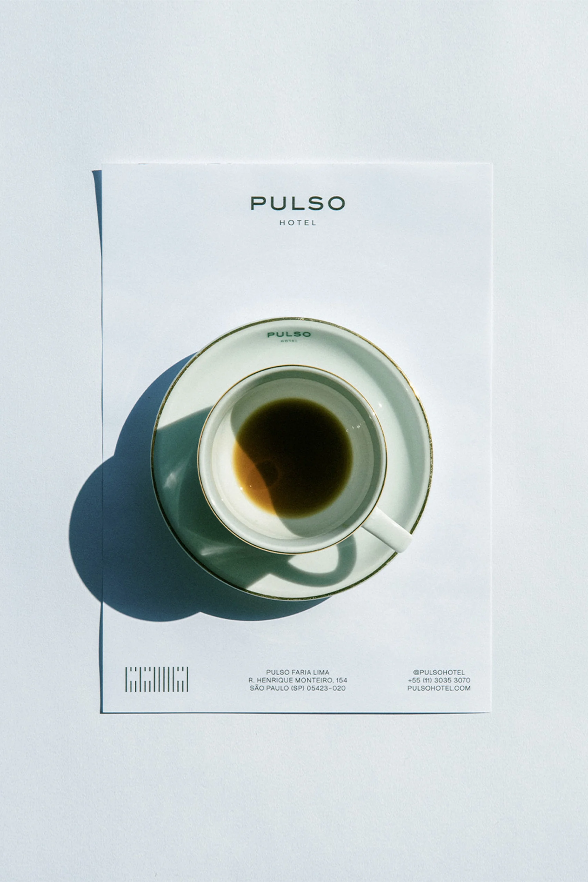 Empty coffee cup and saucer on white paper with hotel logo. Still life composition, minimalist design, indoor shot, bright lighting.