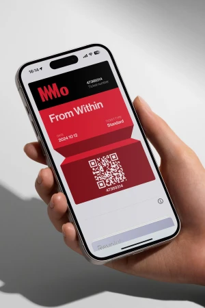 Close-up of a hand holding an iPhone displaying a digital event ticket with a QR code and event details on a white background.