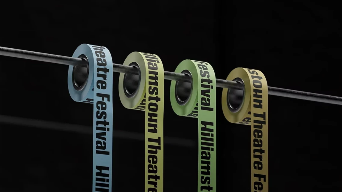 Four rolls of tape suspended from a metal bar displaying the text 'Williamstown Theatre Festival' in colorful artistic style.