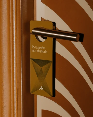 Close-up of a 'Do Not Disturb' sign hanging from a hotel door handle, featuring a geometric design and simple, elegant typography.