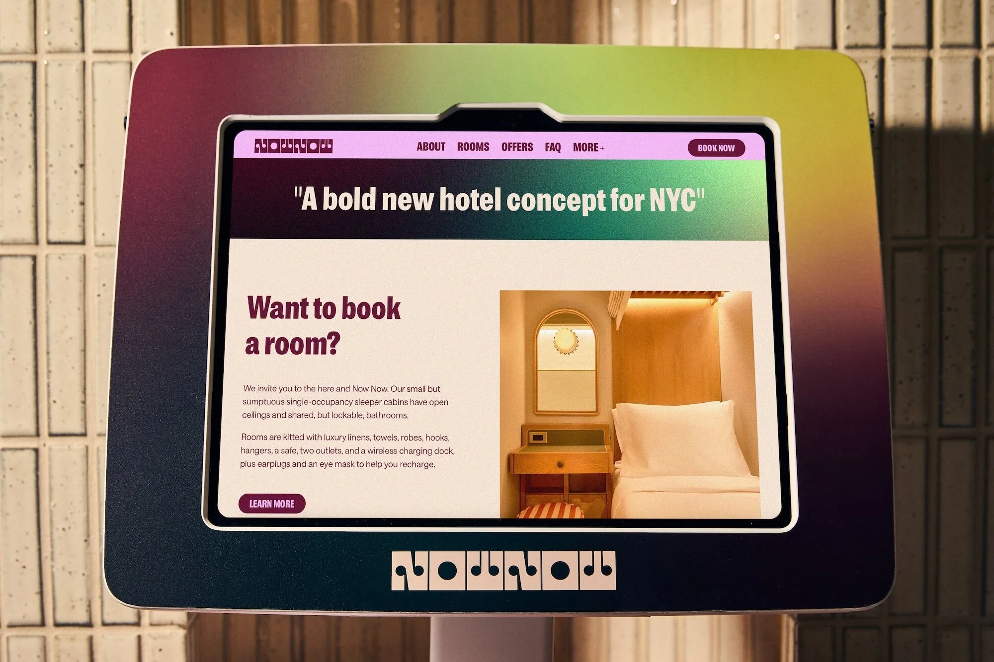Promotional display showing a hotel room interior on a digital screen; the advertisement features travel and modern living concepts.