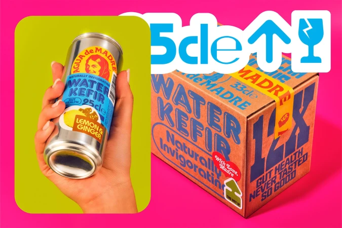 Close-up of hand holding Agua de Madre water kefir can against a two-tone background with shipping box and brand graphics.