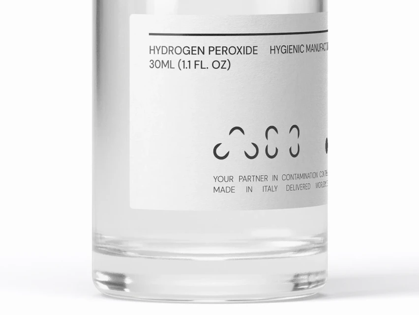 Close-up studio shot of a clear bottle with a white label, featuring the words HYDROGEN PEROXIDE and other product information.