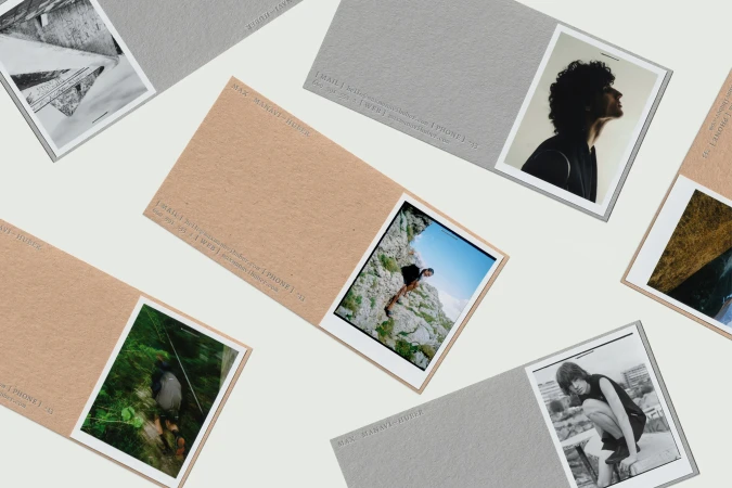 Stack of business cards with Polaroid-style photos featuring fashion, nature, and architecture subjects on a neutral-toned background.