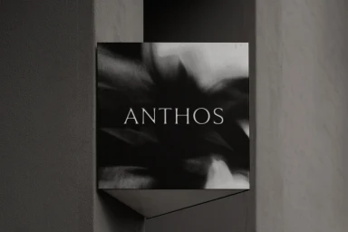 Anthos brand identity signage mounted on a concrete architectural column with monochrome abstract background