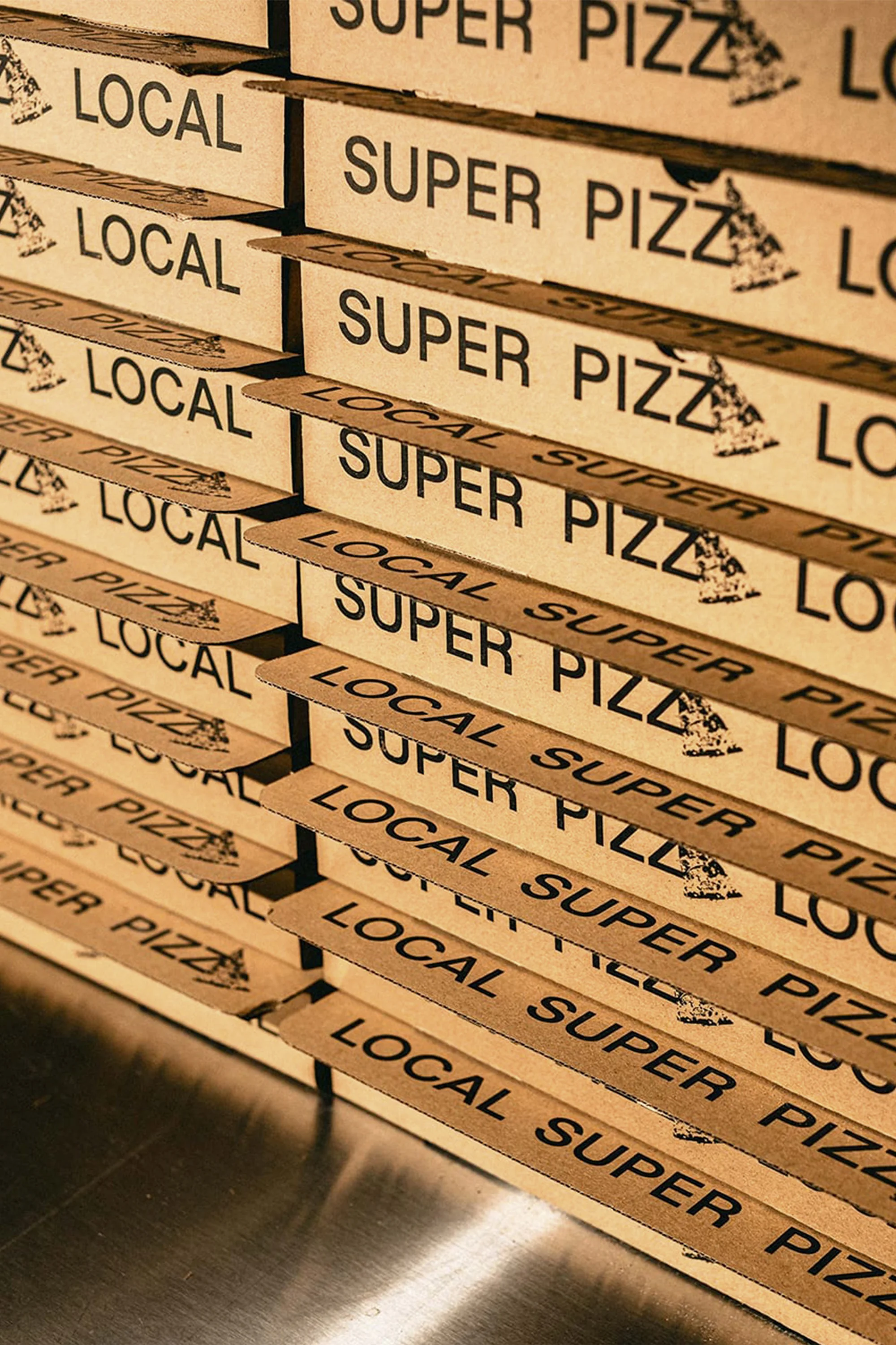 Stack of cardboard pizza boxes labeled 'Local Super Pizza' in a vertical shot, suitable for food and restaurant marketing.