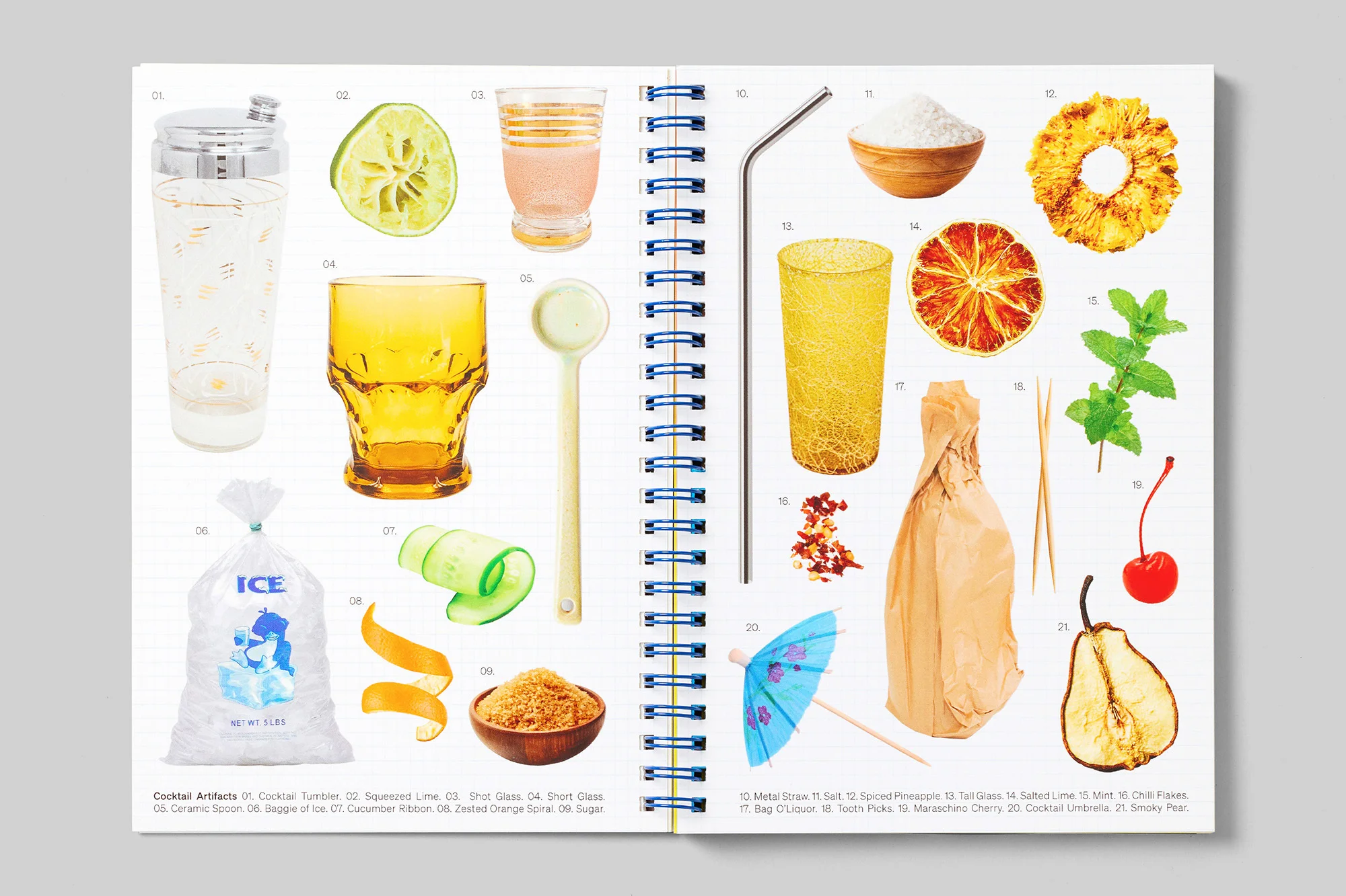 Arrangement of cocktail ingredients on a white surface, featuring citrus fruits, glassware, sugar, and garnishes for mixed drinks.