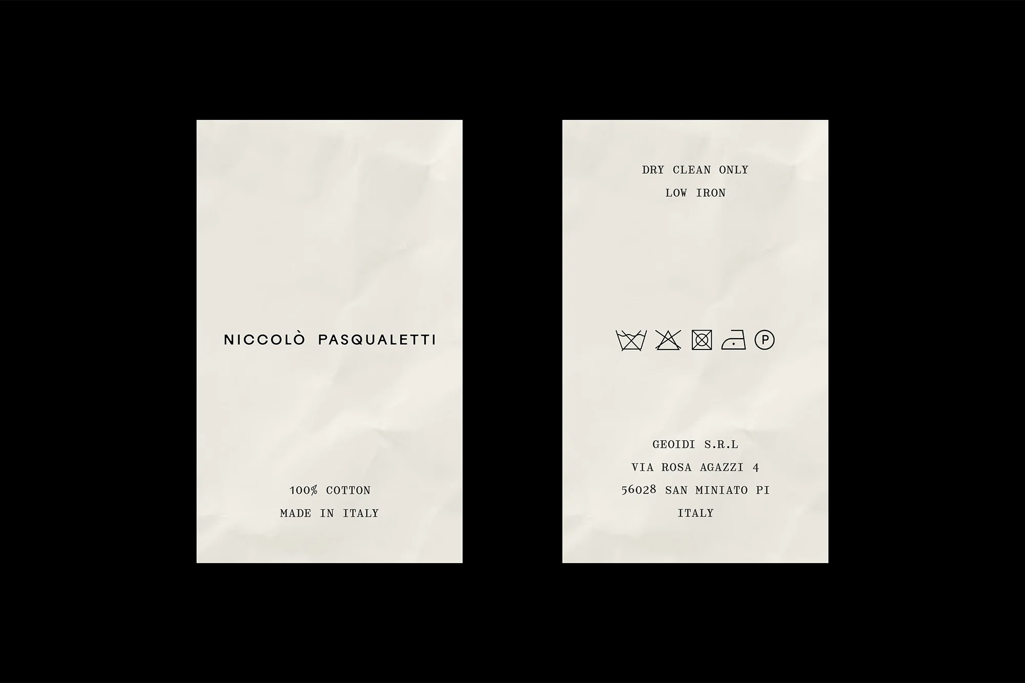 Two clothing tags with care instructions and brand information against a black background in a studio setting.