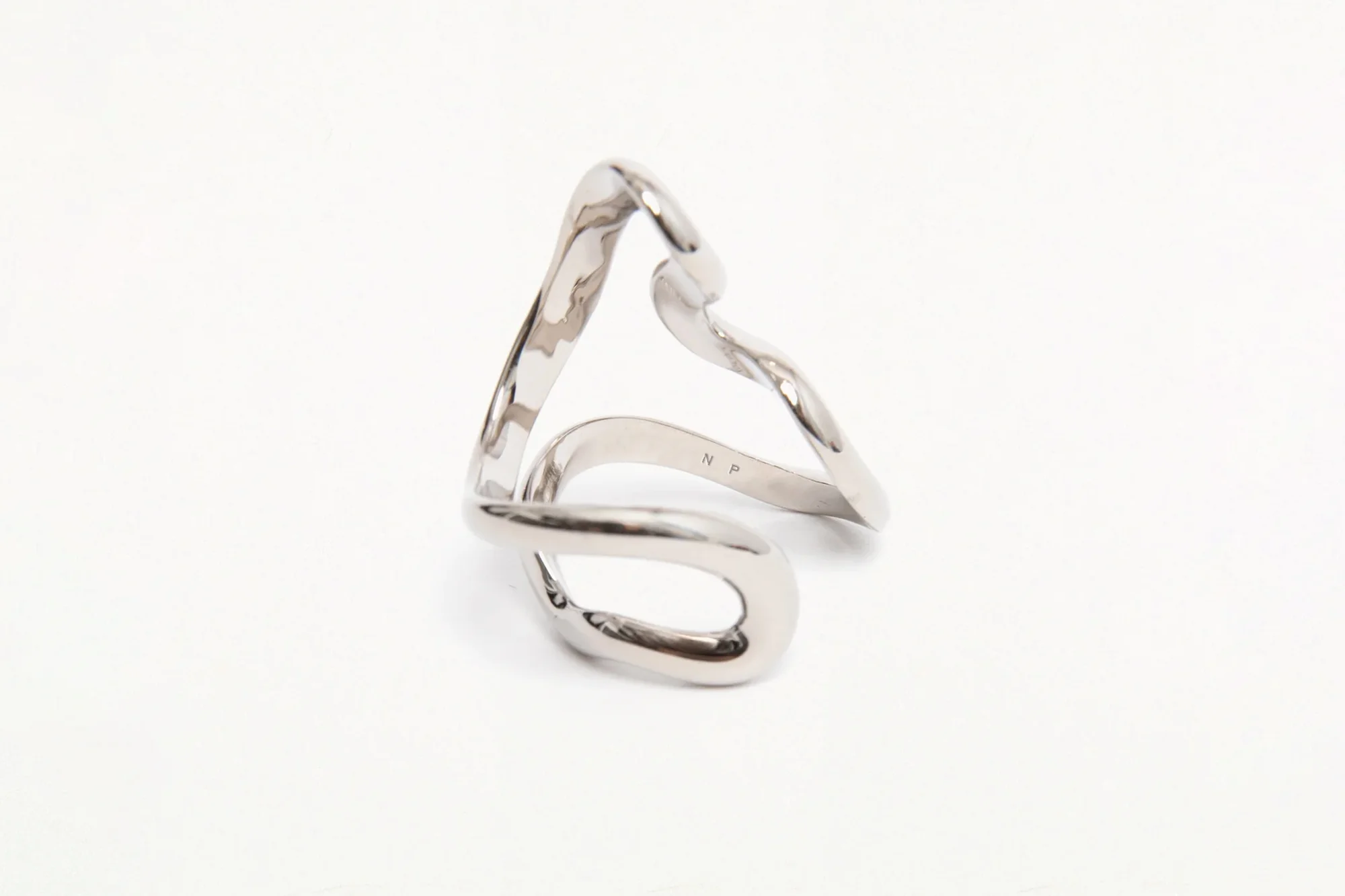 Abstract silver metal ring on a white background, showcasing its fluid, modern design and reflective surface in a close-up shot.