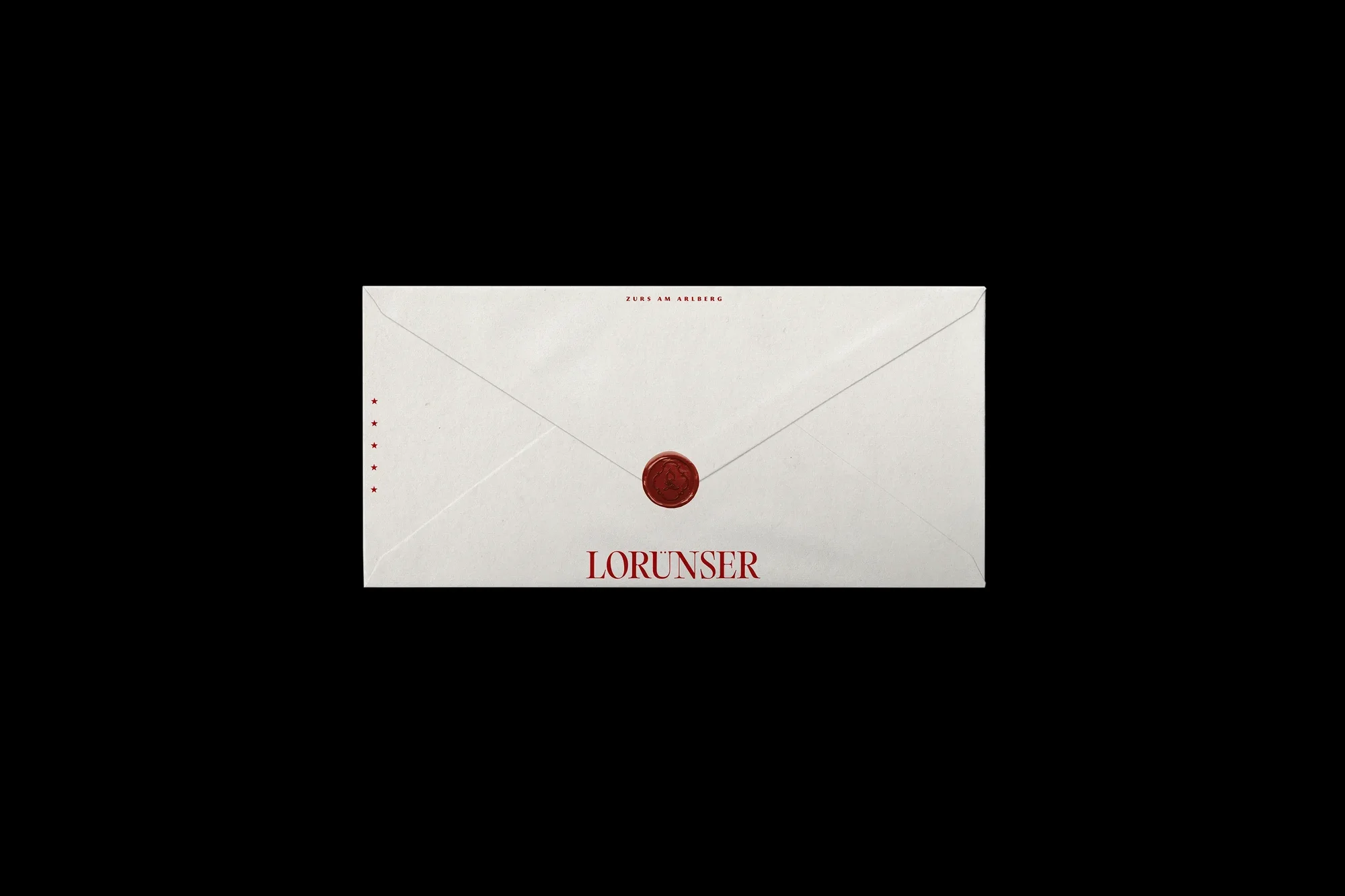 Envelope with red seal and the name Lorunser in red against a black background. Clean, minimalistic product shot.