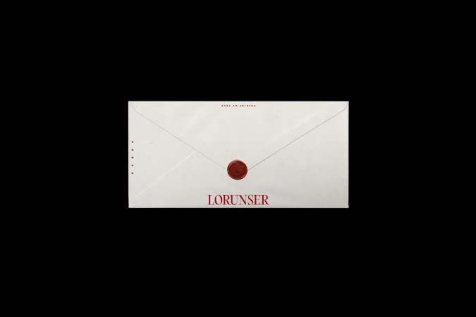 Envelope with red seal and the name Lorunser in red against a black background. Clean, minimalistic product shot.