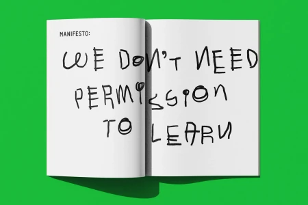 An open magazine lies flat on a vibrant green surface, featuring handwritten text that reads manifesto: we do not need permission to learn.