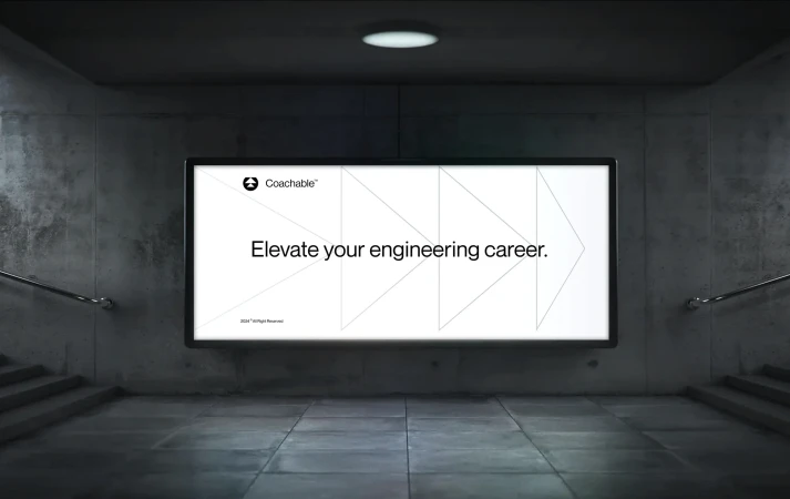 Illuminated billboard advertisement for Coachable in an urban setting, promoting career elevation in engineering.