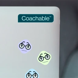 Coachable brand logo sticker and glasses stickers on a silver laptop lid
