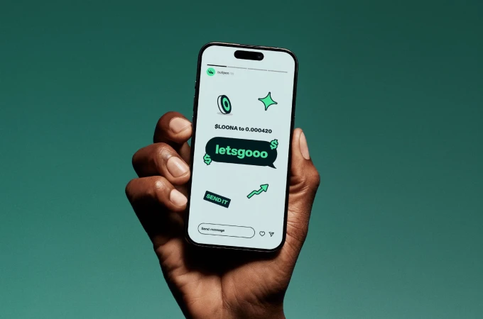 A person holds a smartphone displaying a screen with a green background and digital graphics against a green studio backdrop.