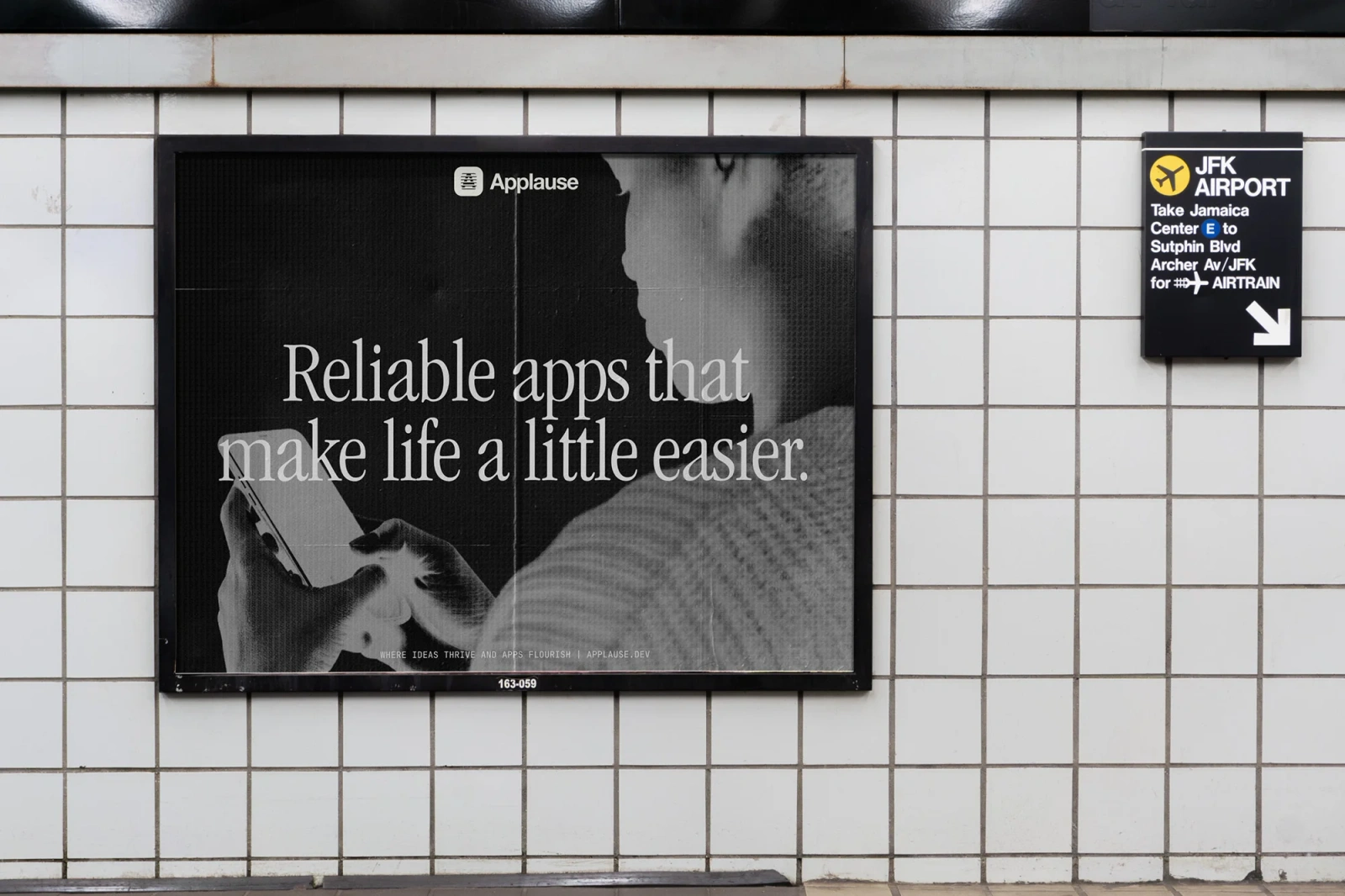 Black and white advertisement poster for Applause displayed on a tiled wall at JFK Airport subway station