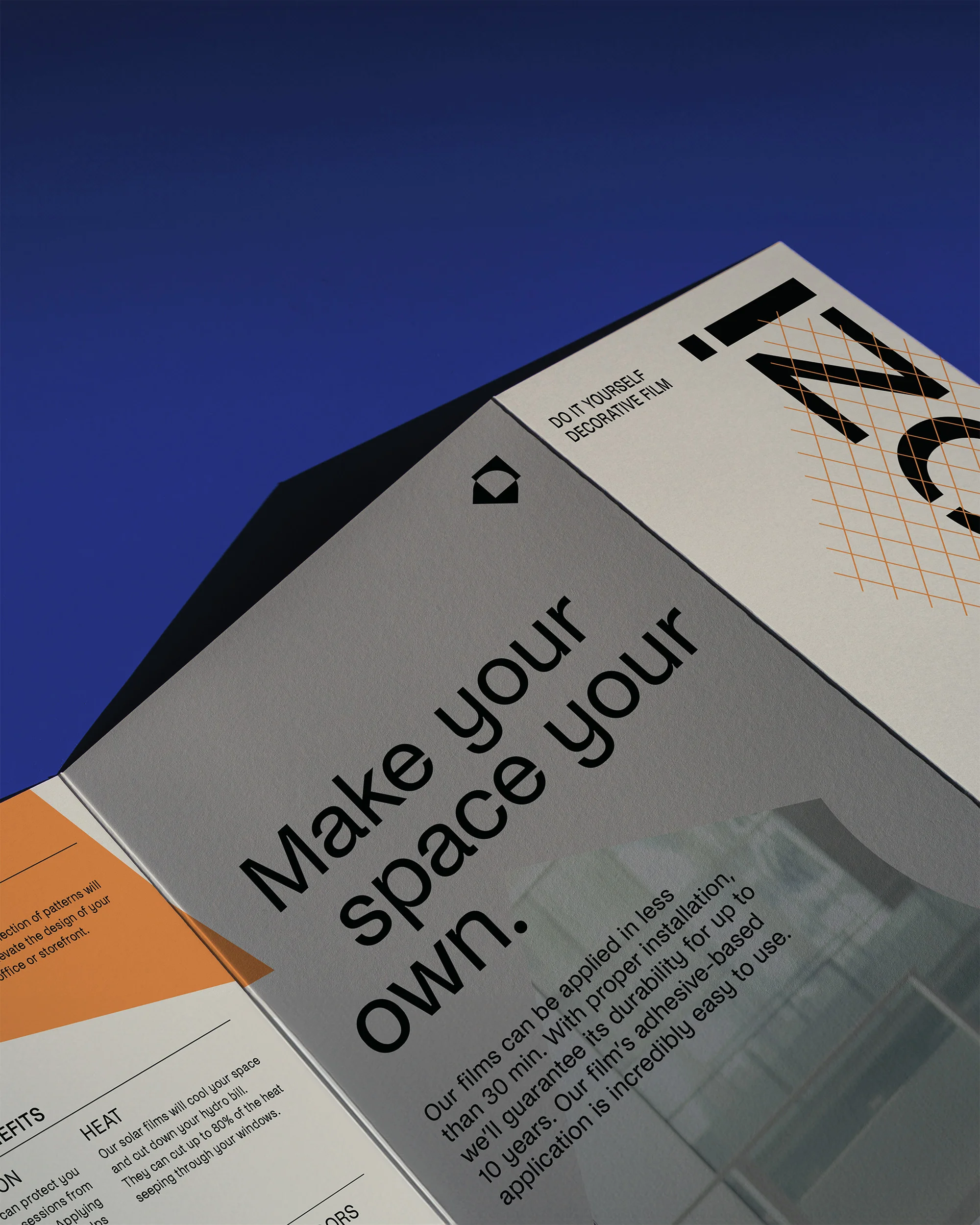 Close-up of a leaflet promoting 'Izon' decorative film, with text 'Make your space your own,' against a blue background.