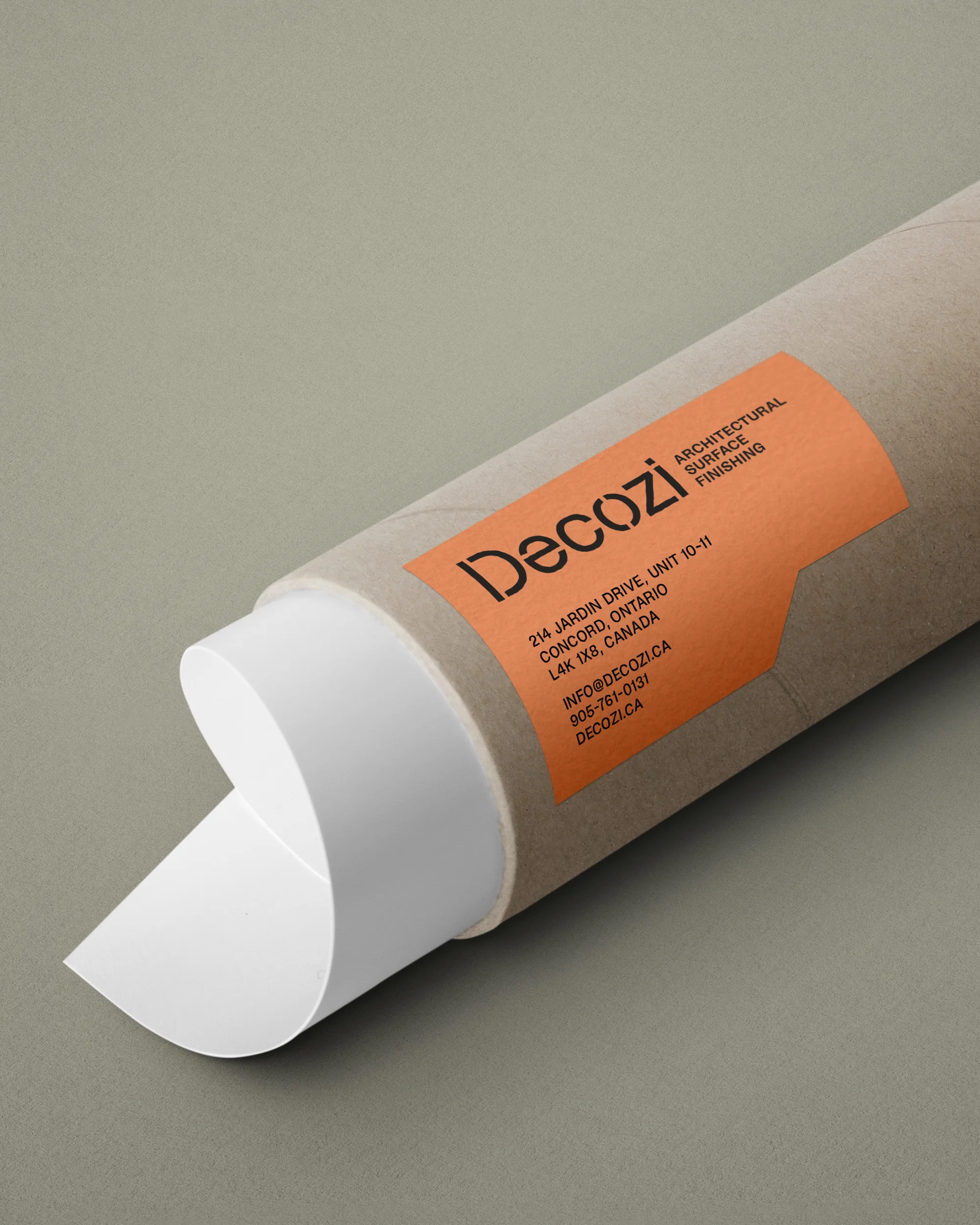 Close-up of an open cardboard tube with an orange label containing brand and contact information against a neutral background.