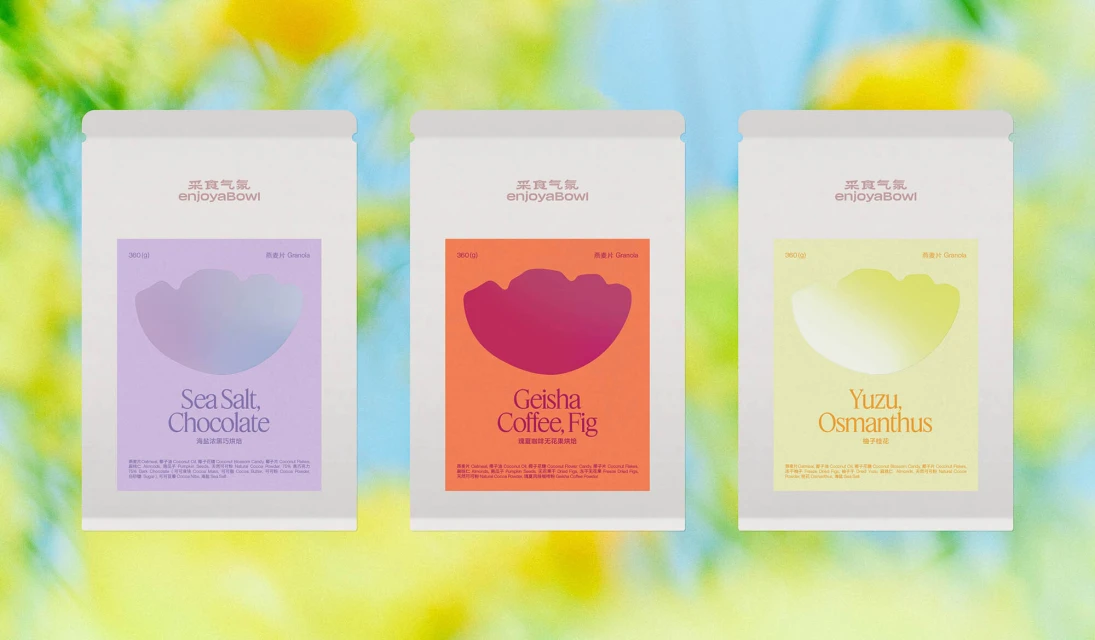Three white enjoyaBowl packages with different fruit flavors and colors against a blurred green and yellow background.