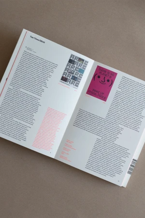 An open magazine displays articles and images, including a pink poster with a smiling face and climate change message.