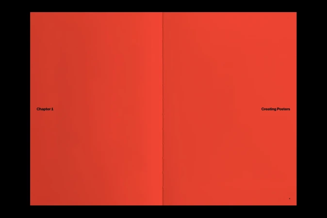 Open book with red pages and black text reading 'Chapter 1' and 'Creating Posters' against a black background.
