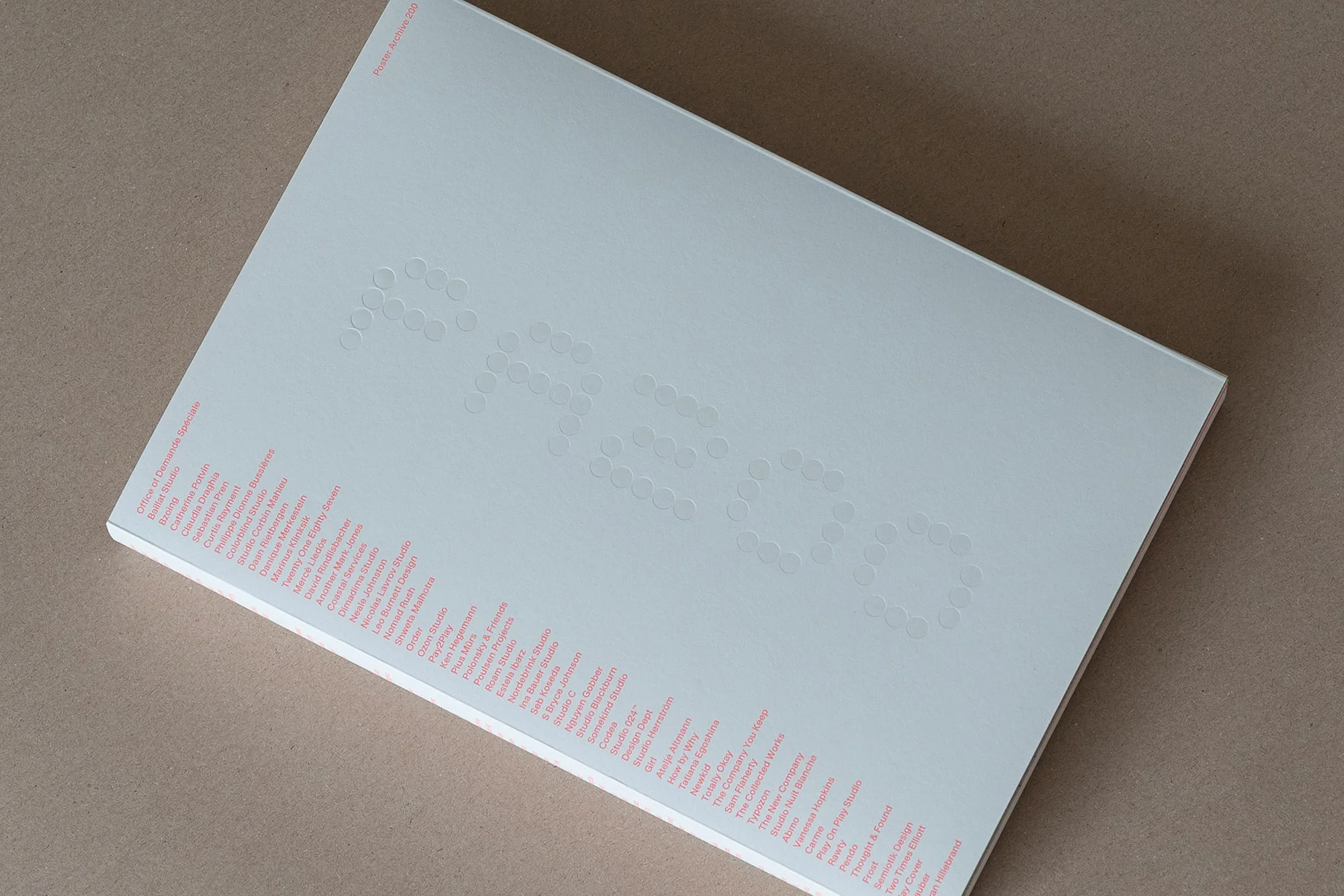 Overhead shot of a white book with embossed title and side text on a neutral background. The book appears minimalist and elegant.