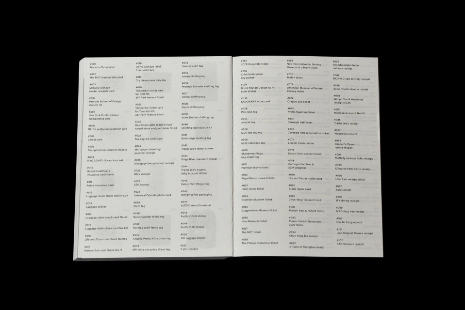 Close-up of two pages of a book featuring small printed text in rows and columns, displayed on a black background.