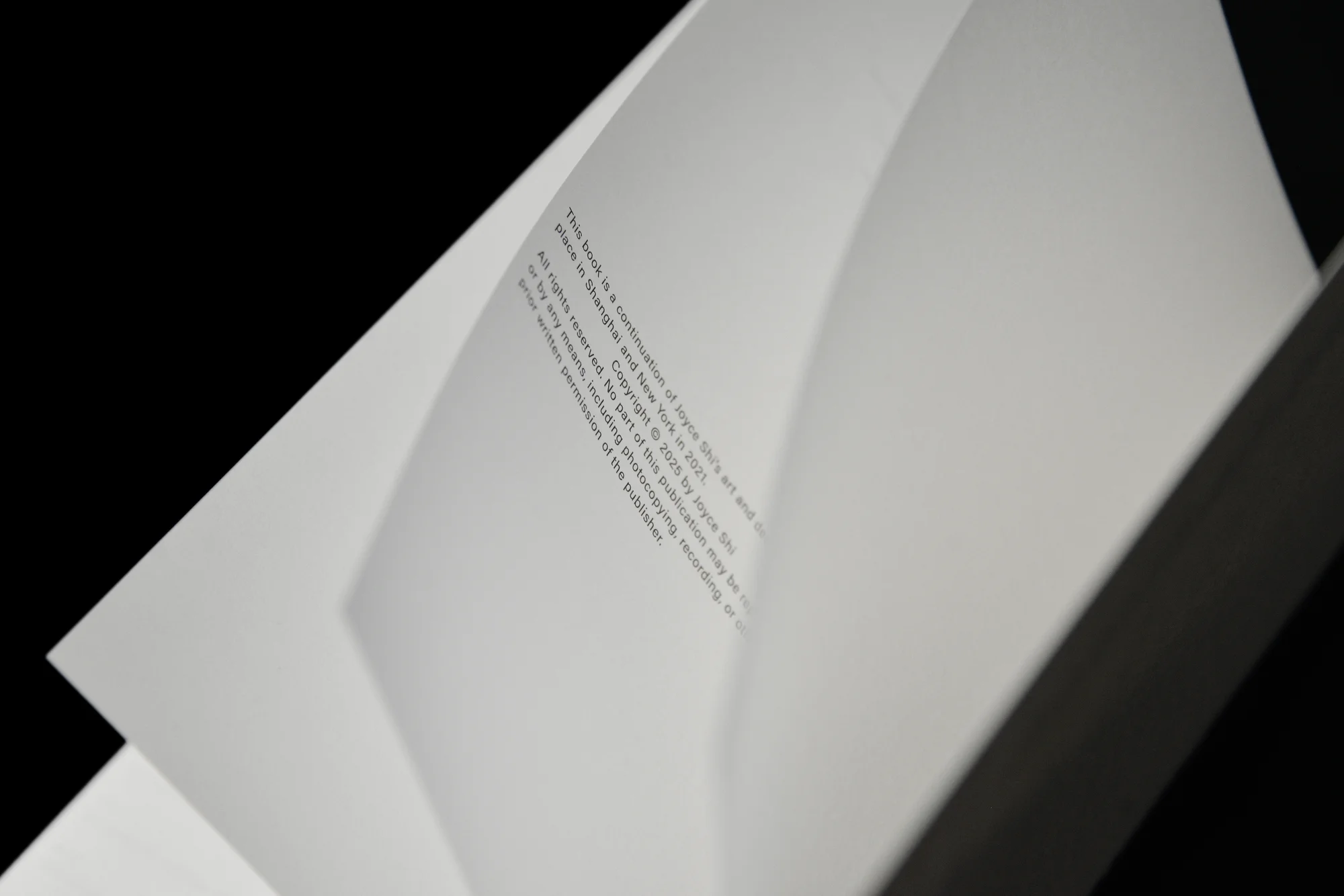 Open book with copyright information in English, including the year and publisher's rights, against a black background. Close-up view.