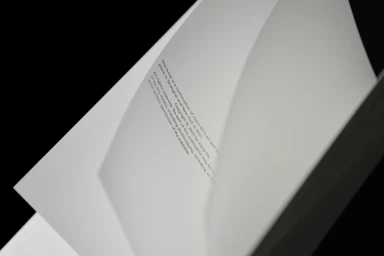 Close-up view of open white paper book pages featuring crisp typography against a dark background.