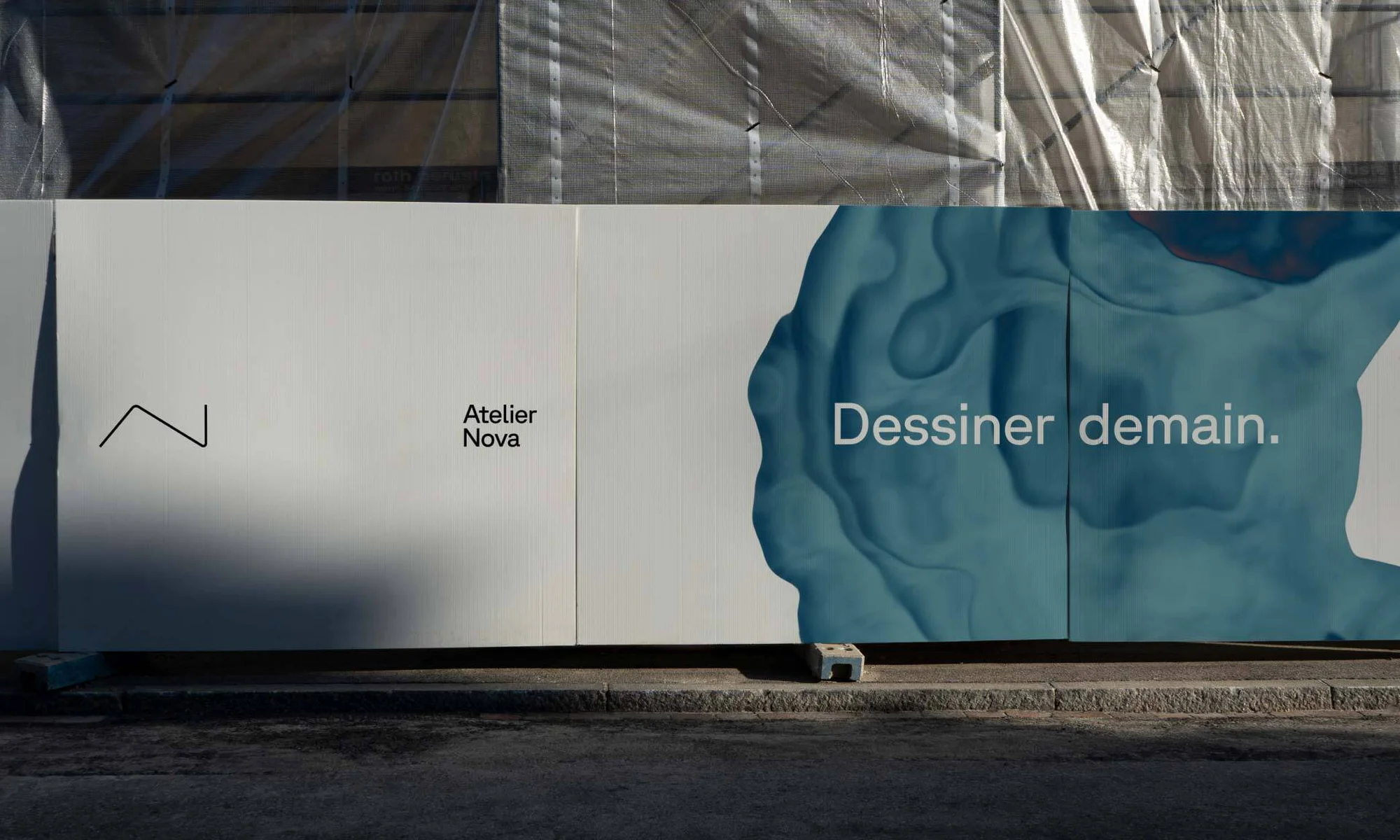 Construction hoarding with Atelier Nova logo, abstract water design and 'Dessiner demain' text, urban setting, daytime, under tarp.