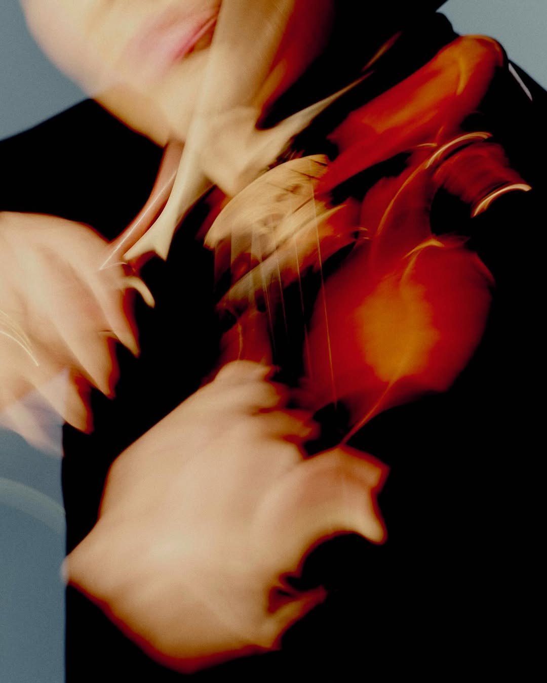 Blurred image of a person playing the violin in a dark room, featuring motion blur and warm color tones, artistic effect.