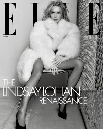 Blonde woman in fur coat sits on chair against chain-link fence for Elle magazine cover with 'The Lindsay Lohan Renaissance' text.