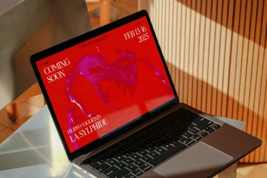 Laptop computer displaying a red digital branding screen for Cincinnati Ballet on a metal table.