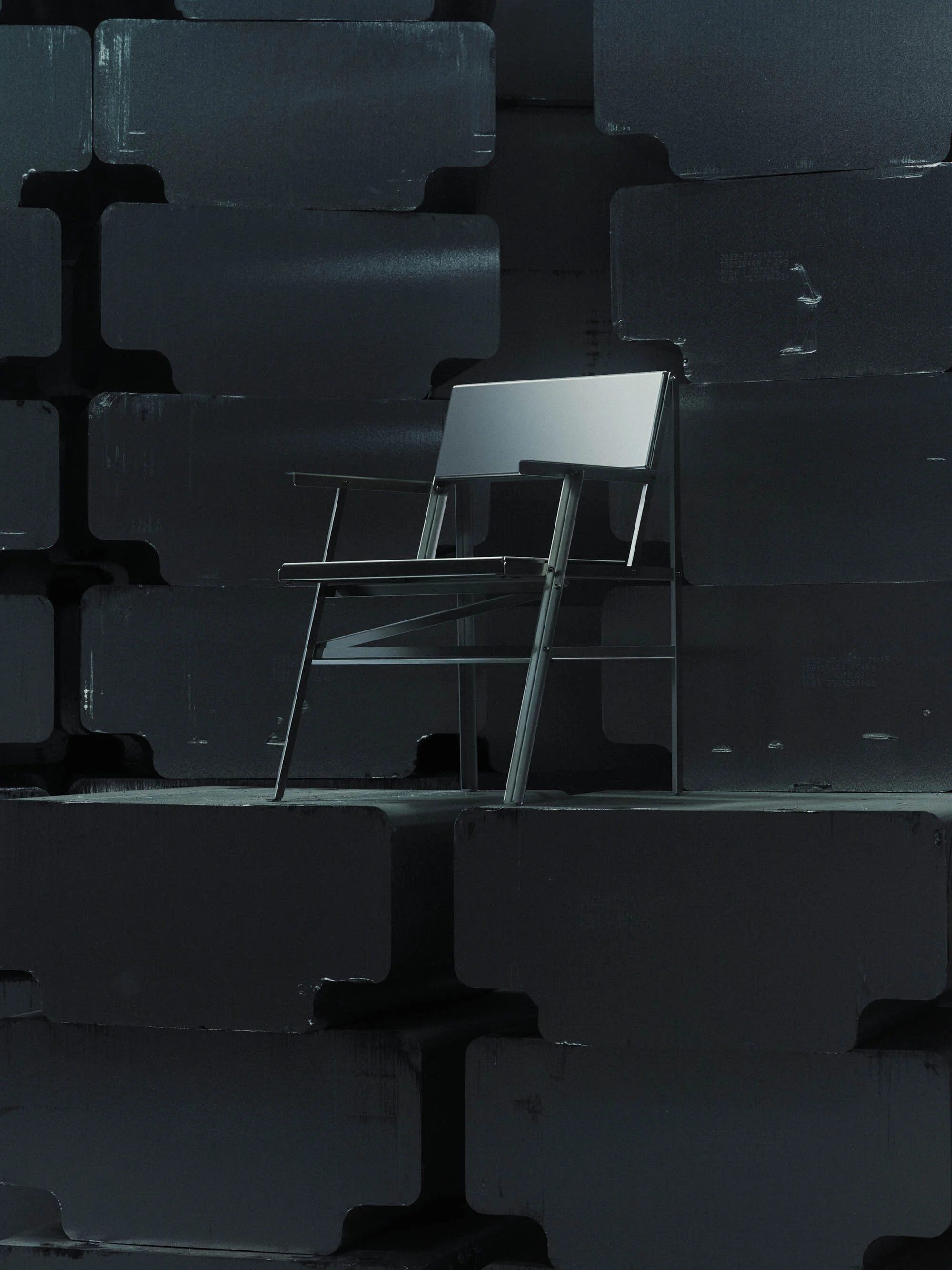 Modern metal chair stands out against a stacked block wall in a studio setting with dark gray lighting, emphasizing design and structure.