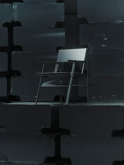 Modern metal chair stands out against a stacked block wall in a studio setting with dark gray lighting, emphasizing design and structure.
