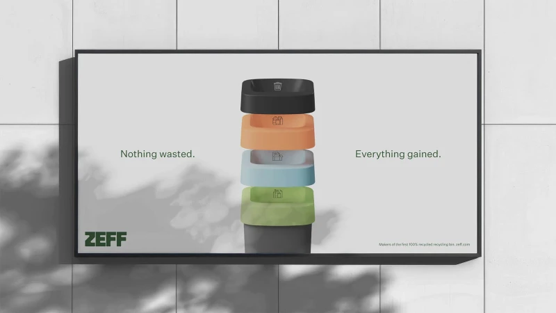 Conceptual advertisement for a recycling company featuring stacked recycling bins on a poster against a textured grey wall with light shadows.