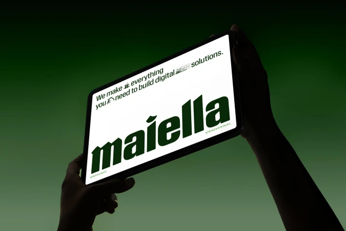 Digital tablet displaying Maiella digital solutions held by hands against a green background, showcasing digital technology and services.