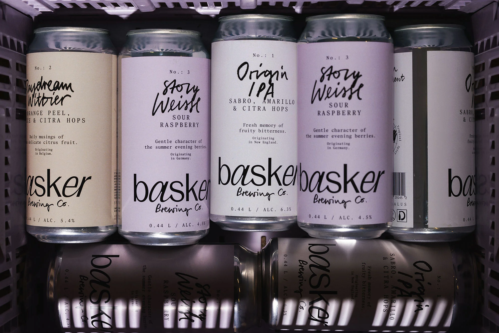 Cans of Basker Brewing Co. craft beer in a cooler, featuring Daydream Wittier, Story Weisse, and Origin IPA varieties with visible ingredient details.