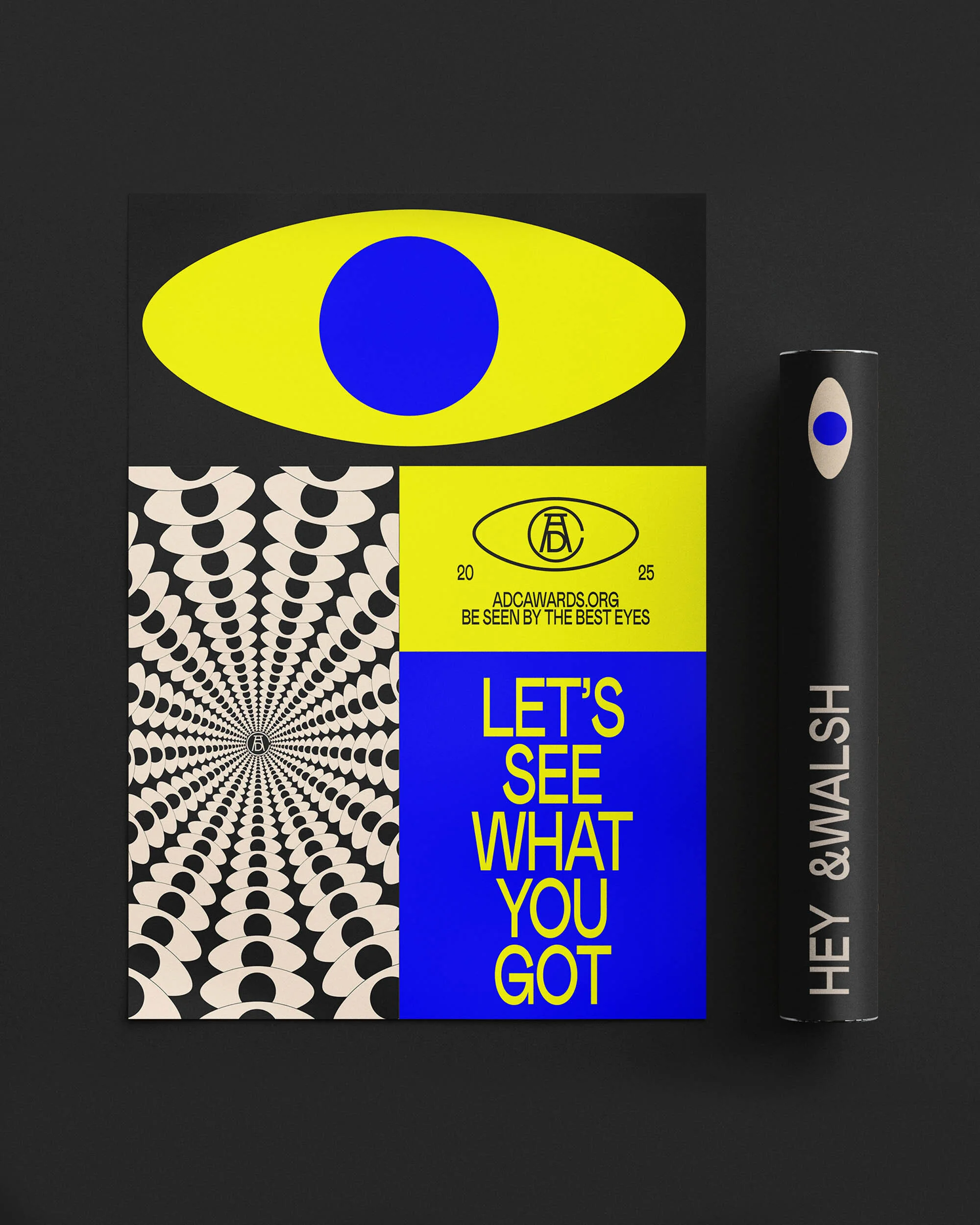 Abstract graphic design featuring a yellow eye, radial pattern, and typography on a black background in a studio setting.