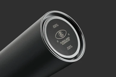 Close-up of a matte dark grey cylindrical container featuring the ADC brand logo and typography on its circular base against a dark background.