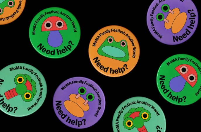 Colorful MoMA Family Festival buttons display whimsical cartoon creatures and the question, 'Need help?' over a stark black background.