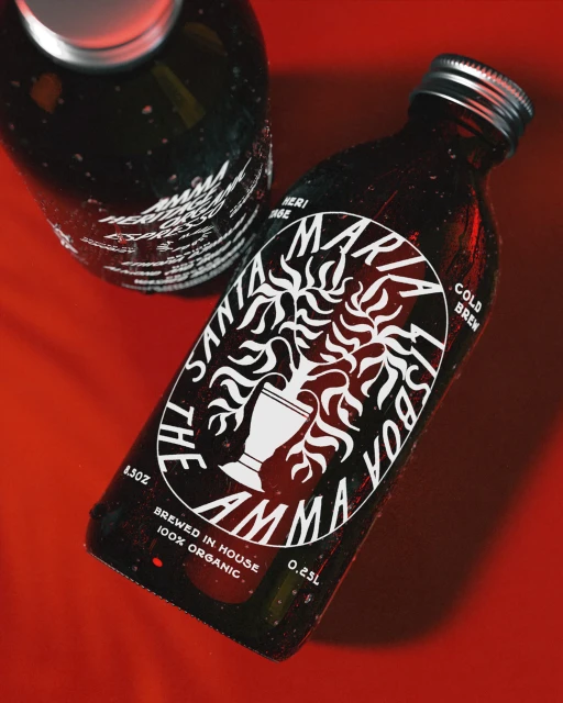 Close-up of two dark glass bottles featuring white labels with a logo of a stylized goblet and the brand name in bold font.