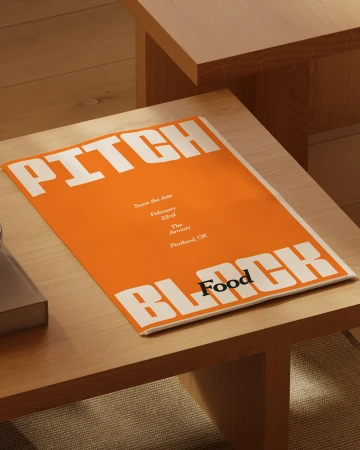Promotional flyer on a table featuring the words 'Pitch Black Food,' with event details for February 22nd in Portland, OR.