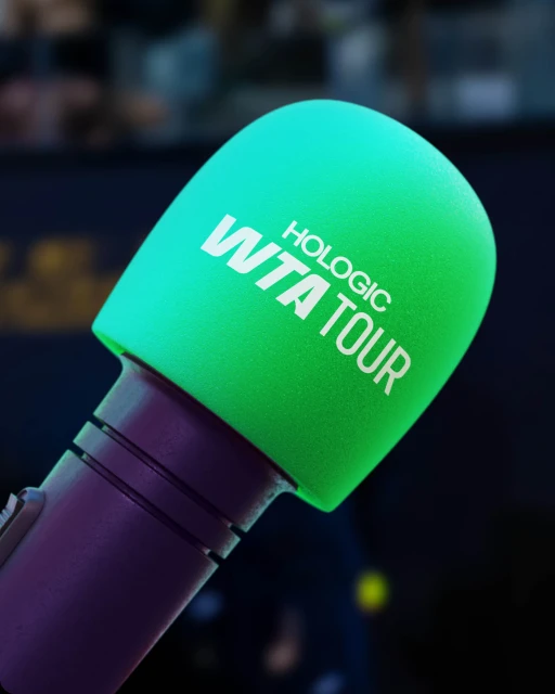 Close-up of a green microphone with the words Hologic WTA Tour, used for sports broadcasting, set against a dark background.