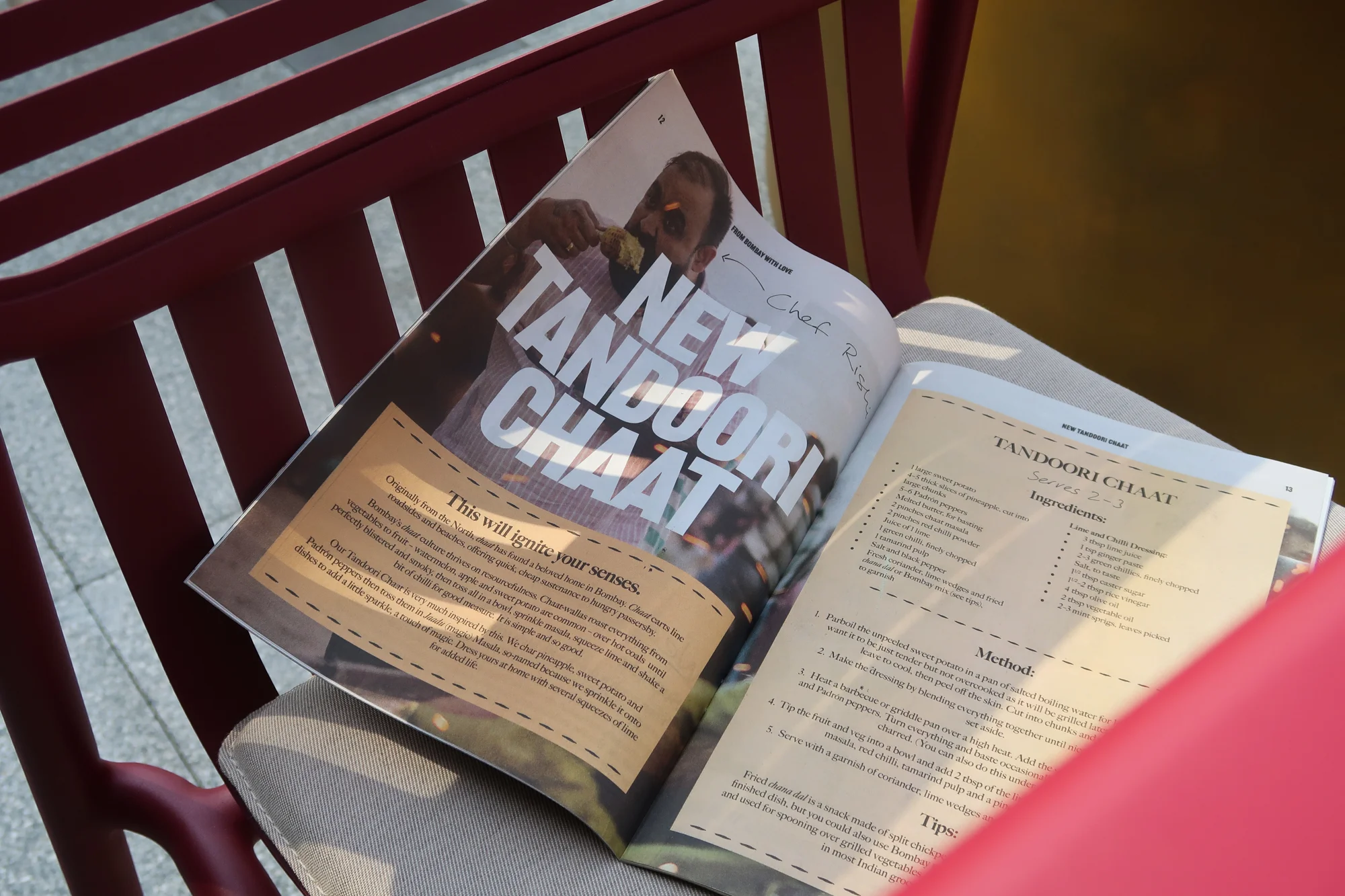 Open magazine on a red chair with a focus on Indian cuisine, showcasing a recipe for Tandoori Chaat with visible food imagery and text.