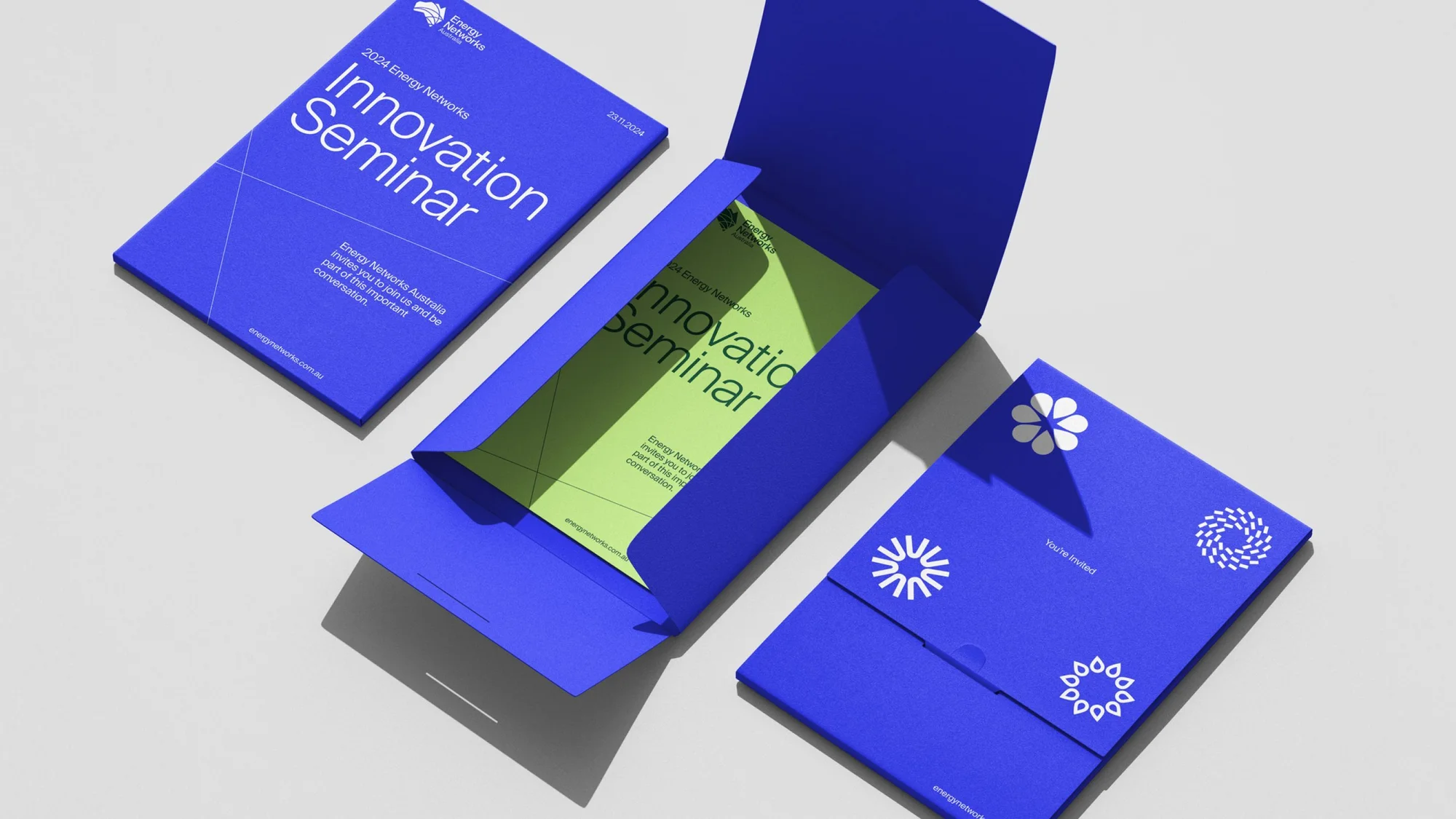 Graphic design invitation featuring blue cardstock with floral designs and geometric blue and green printed invite for 2024 Innovation Seminar.