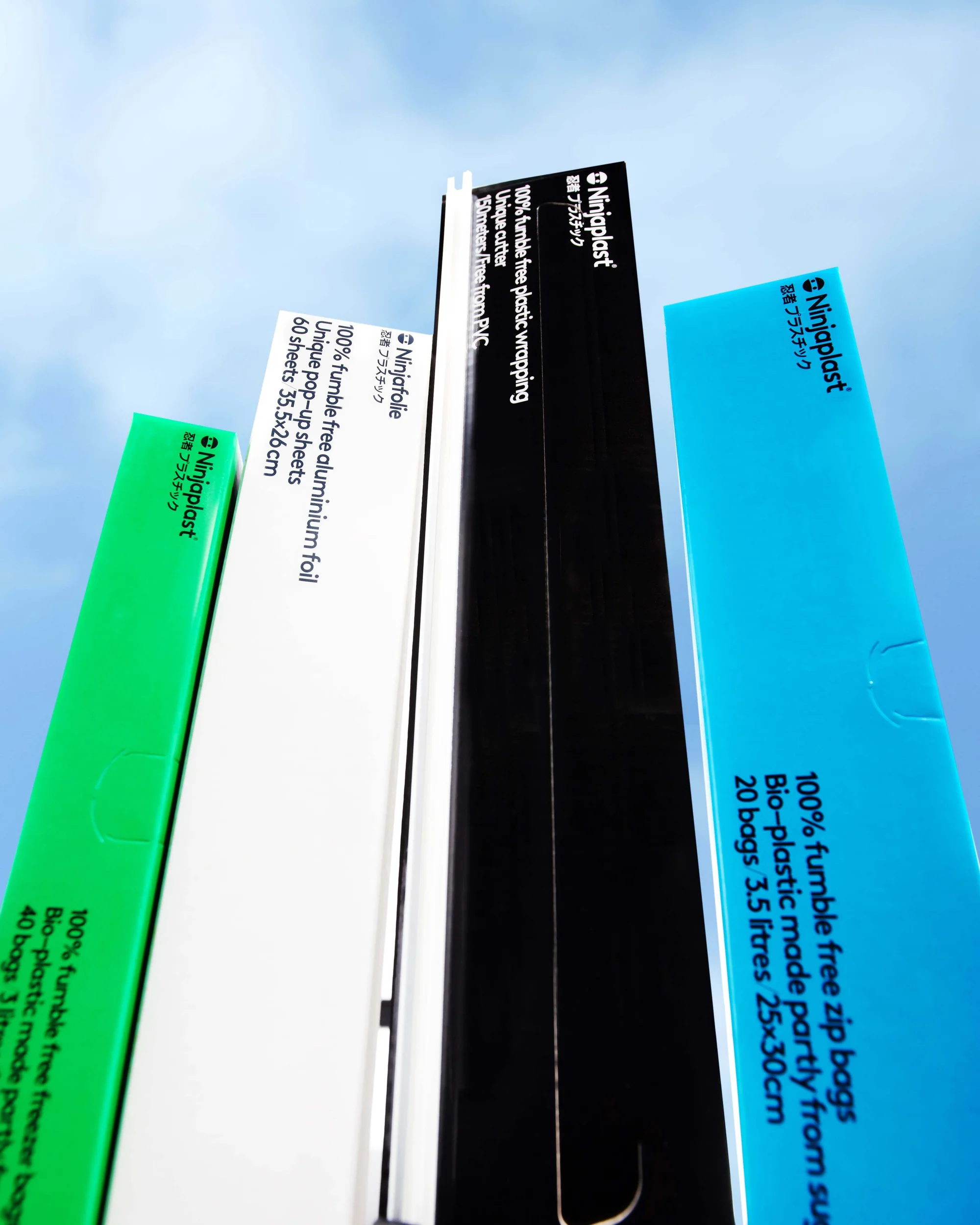 Five colorful product boxes of Ninjaplast food storage solutions are angled against a bright blue sky backdrop, showcasing their branding.